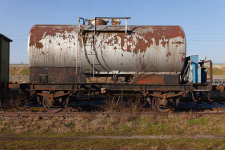 Old train cistern tank wagon, rusty and weathered on abandoned train tracks in the fieldの写真素材