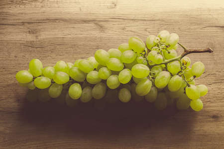 Beautiful cluster of white grapes on wooden kitchen tableの写真素材