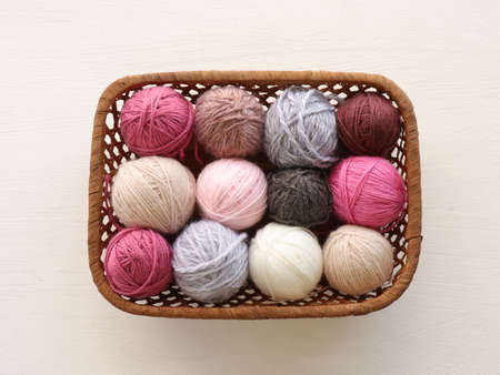 Multicolored knitting yarn balls in basket on white background