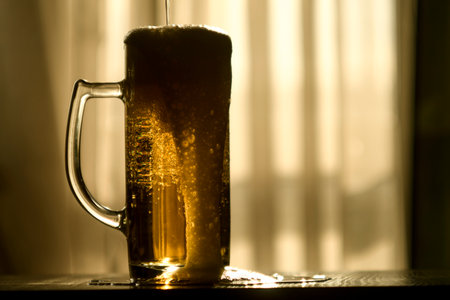 Glass mug of foamy beer. Bubbles are visible through the drink. Illuminated by sunset soft orange light.の写真素材
