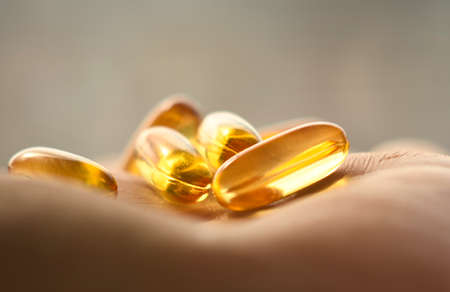 Yellow capsules of fish oil on the hand. Close-up.の写真素材