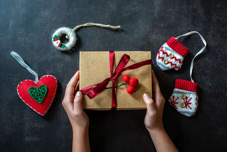 Hands hold christmas gift box on dark backround, new year gift box in childs hands, christmas decorationの写真素材