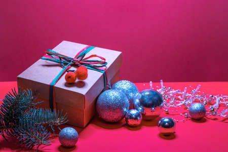 Christmas gift box, pine tree branch and silver christmas baubles on red backgroundの写真素材