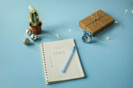 Christmas gift box with cactus decorated with Christmas lights and alarm clock on blue backgroundの写真素材