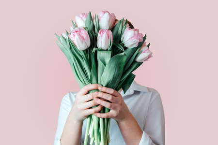 A girl covering her face with a bunch of pink tulip flowersの写真素材