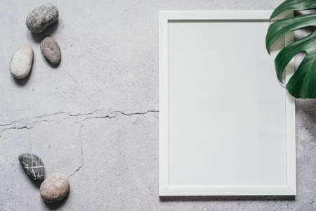 White frame photo with monstera leaves and pebble stones, blank frame poster with tropical leavesの写真素材