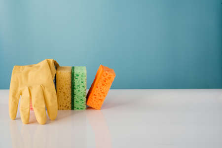 Colorful cleaning sponges with soap bubbles on blue background. Cleaning service and spring cleaning conceptの写真素材