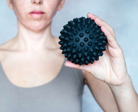 A woman holds a spiky trigger point massage ball used for muscle pain treatment and deep tissue massageの写真素材
