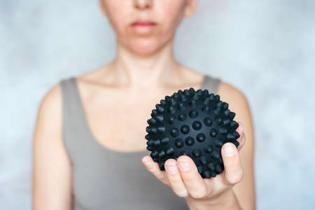 A woman holds a spiky trigger point massage ball used for muscle pain treatment and deep tissue massageの写真素材