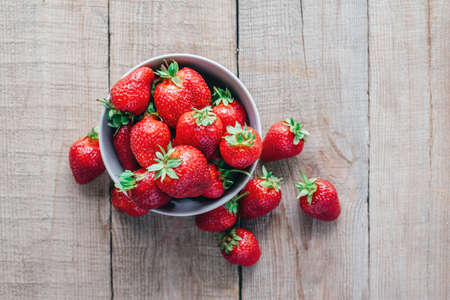 Delicious ripe strawberry in a bowl on wooden table top view, summer flatlay with healthy summer...