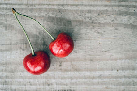 Delicious sweet cherry close-up on the wooden table top view, summer fruits high on vitamins and antioxidantsの写真素材