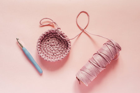 Crochet hook and pink color yarn on a pink background, knitting and crochet supplies, hobby and...
