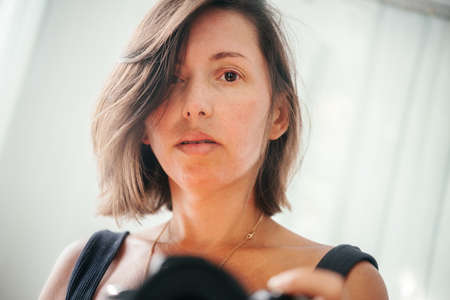 A woman taking a selfie with a DSLR camera in front of the mirror