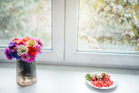 A bouquet of autumn flower with guelder rose berries on the windowsillの写真素材
