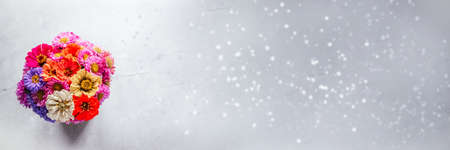 A bouquet of zinnia and aster autumn flowers on gray cement backgroundの写真素材