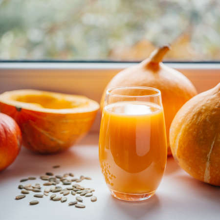 A glass of pumpkin juice with pumpkin seeds on a windowsillの写真素材