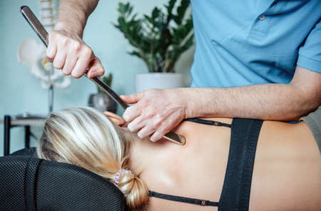 Chiropractor performing myofascial release techniques with IASTM tool for the Rhomboidsの写真素材