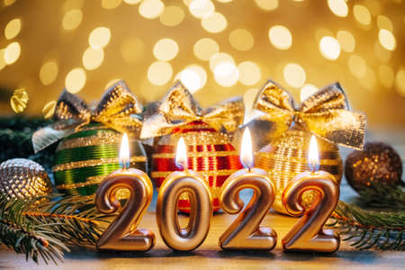 Happy New Year 2022, golden numbers 2022 burning candles, Christmas tree balls with golden bows and...