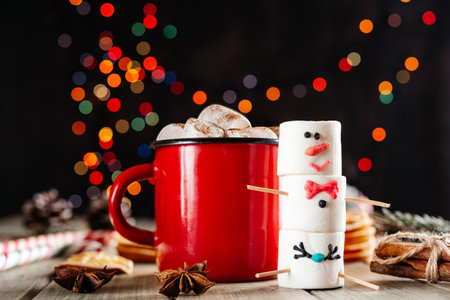 Red enamel mug of hot chocolate with marshmallow snowman on Christmas backgroundの写真素材