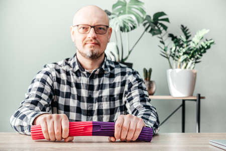 A man doing wrist exercises with theraband flexbar
