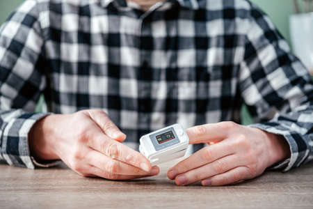 A man checking oxygen level at home with home oximeter, patient measuring the blood oxygen with oximeterの写真素材