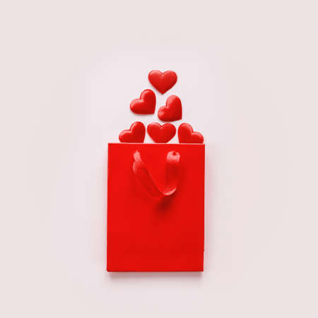 Red shopping bag with red textile hearts on pink Valentines day background