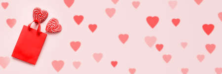 Red shopping bag with two heart shaped lollipops on pink Valentines day background banner sizeの写真素材