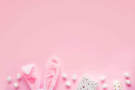 Easter shopping composition with bunny ears, gift box and Easter eggs on pink backgroundの写真素材