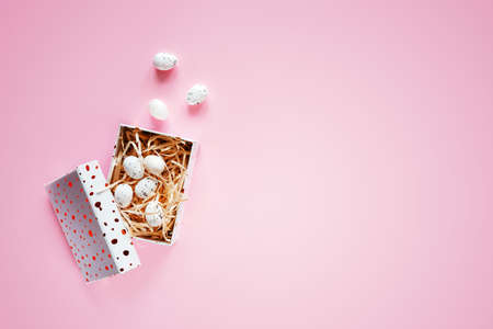 Minimal Easter background with Easter eggs in a gift box on pink background