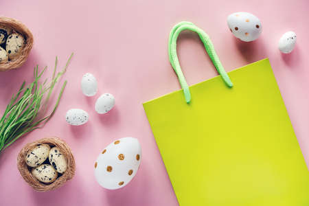 Easter shopping background with green shopping bag with Easter eggs and birds nest on pink...