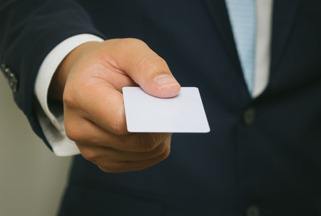 Business man handing a blank business card over white backgroundの写真素材