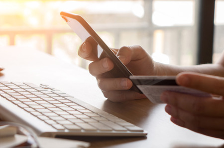 Hands holding credit card and using phone. Online shoppingの写真素材