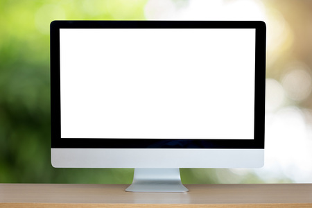 Computer over wooden table on natural green blurred background