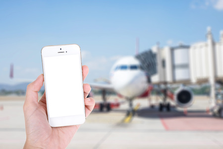 Woman hand showing smart phone with isolated screens display with blur airplane in the airport backgroundの写真素材