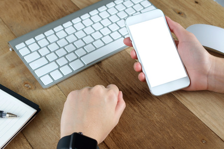 woman hand holding empty screen of smart-phone on wood desk work.の写真素材