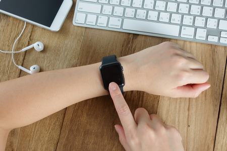 Woman Using Touchscreen Smart Watch at work desk