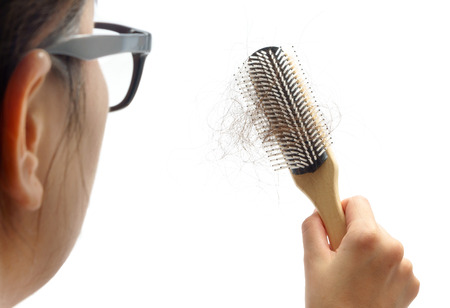 woman losing hair on hairbrush isolated on whiteの写真素材