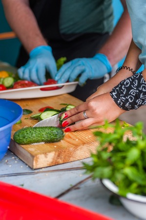 Women's hands cut fresh vegetables with a sharp knife.の写真素材
