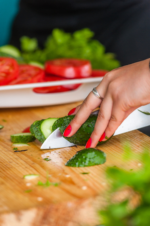 Women's hands cut fresh vegetables with a sharp knife.の写真素材