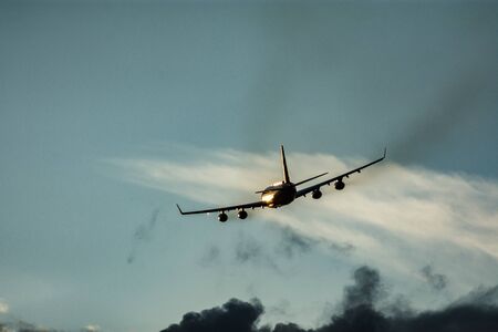 Airplane take off at sunset with cloudsの写真素材