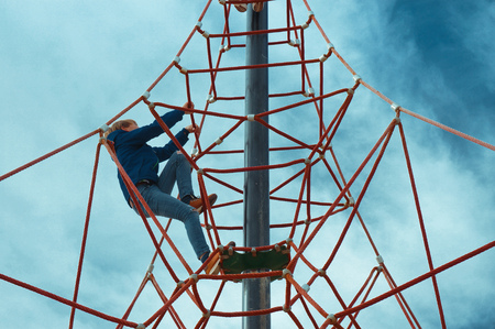 Child climbing on rope pyramide playground on the beachの写真素材