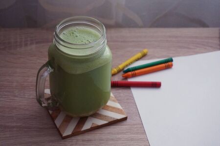 Green healthy vegan smoothie in mason jar on deskの写真素材