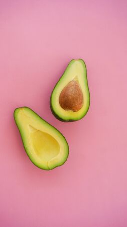 Avocado cut in halves on pink background vertical orientationの写真素材