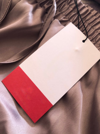 White and red price tag on silk beige fabric close up