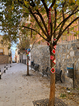 Tibi, Spain - December, 2024: Winter trees on streets of small Spanish town decorated with knitted peacesの写真素材