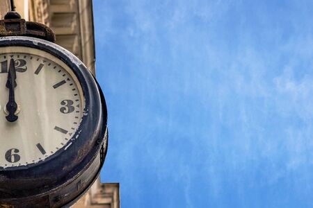 Street vintage clock on an old building against a blue sky with aerial clouds. Part or a Half of the dial of retro watches close up. Twelve hours.の写真素材
