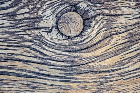 Striped texture of an old wooden surface with a big knot, cracks and traces of atmospheric effects....