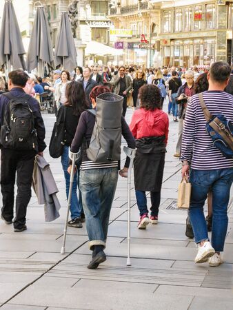 Austria, Vienna - may 2019:  Injured woman with their walking sticks is purposeful traveler. Tourist walk through the center of the city with walking canes. Active lifestyle of an elderly person.のeditorial素材