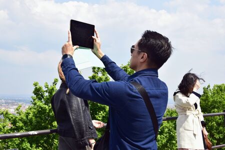 Budapest, Hungary - may 2019: Young man takes a picture with a tablet of a picturesque view of the...