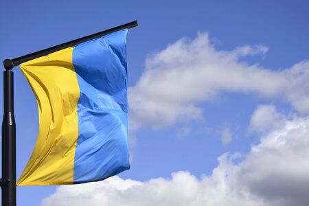 Ukrainian flag on flagpole against the blue cloudless sky. The official flag of the Ukrainian state...
